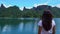 The girl is standing on the pier on the lake and looking into the distance.