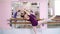 Girl standing at railing in ballet hall. Young ballerina stretching out using ballet barre in studio. Young ballerina in