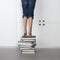 Girl standing on top of a stack of books