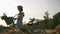 Girl is standing with vintage retro bike in meadow in sunshine. Woman cyclist walks and rolls old fashioned bicycle through field.