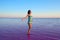 Girl standing in water of pink salted lake in Altai