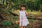 Girl standing in the woods holding a toy bear in hand