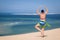 Girl in a standing yoga pose in the beach