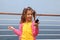 Girl stands on board ship holds portable radio