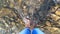 Girl stands at the bottom of a rocky shallow river in the mountains