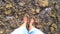 Girl stands at the bottom of a rocky shallow river in the mountains