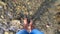 Girl stands at the bottom of a rocky shallow river in the mountains