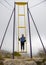 A girl stands on an extreme swing against the backdrop of misty mountains