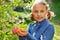 A girl stands in the garden by a spring tree and holds Easter eggs in her hands