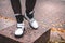 A girl stands on granite on a beautiful tile background in white warm boots