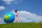 Girl stands on grass and plays with globe