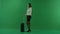 The girl stands on her left side, next to the suitcase and talking on the phone on green screen