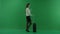 The girl stands on her right side, next to the suitcase and drinks something on green screen