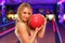 Girl stands and hugs ball in bowling club