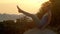 Girl stands in navasana on large rock at sunrise slow motion