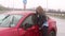 Girl stands near the broken car in the rain, she is wounded and holds her head.