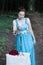 Girl stands near a table with red roses and keeps a candlestick