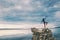 The girl stands on a pile of stones and looks at the sea