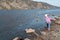 Girl stands on the riverside and feeds a flock of wild ducks swimming in the Yenisei river against the rocky shore