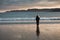 A girl stands on the shore of the Barents Sea at sunrise