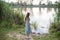 A girl stands on the shore of the lake and looks at nutria in the water