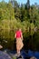 A girl stands on stone on the shore of a forest lake. Vertical autumn photo