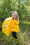 A girl stands on a street in a yellow raincoat with an umbrella in his hand thinking