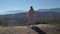 A girl stands on top of a mountain and enjoys the beauty of the highlands.