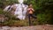 Girl stands in yoga position on flat stone by waterfall