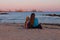 Girl staycation picnicking on sea sand beach with amazing colorful sunset background.Trend local travel.Evening seascape