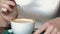 Girl is stirring coffee with a spoon while in a cafe, spoons drop coffee drops in a mug, close-up, slow motion