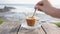 girl stirring latte on table at beach cafe outside