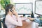 Girl stockbroker trades online by taking orders over the phone. Two white computer screens with graphs.