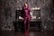 Girl in strange futuristic costume posing with old vintage black piano in dark gothic room with candles alone