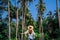 Girl in straw against the background of tropical coconut trees and blue sky. Walk in the Rainforest on the island of Koh Samui