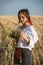 Girl on straw field with wildflower bouquet on hand