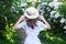 Girl in a straw hat with a blue ribbon on a spring afternoon. Back view. Trendy casual summer or spring outfit. Street fashion. Wo