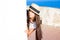 Girl in straw hat peeks out from behind wall