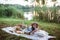 A girl in straw hat is on a picnic in a park on the banks of a river