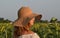 The girl in the straw hat in profile on the field with sunflowers.