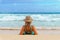 Girl in a straw hat relaxing on the sandy beach and looking at the stormy sea