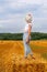 girl in straw hat stands on a haystack on a bale in the agricultural field after harvesting