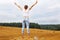 girl with straw hat stands on a haystack on a bale in the agricultural field after harvesting