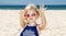 Girl in striped swimsuit on a white beach showing sandy hands