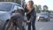 A girl stroking a black stray dog.