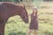 Girl stroking her horse and looking at the camera