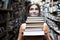 Girl student holds a stack of books in the library, she searches for literature and offers to read, a woman prepares for study,