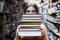 Girl student holds a stack of books in the library, she searches for literature and offers to read, a woman prepares for study,