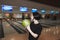 Girl student playing bowling. A look before the throw in the bowling game against the background of the tracks