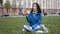 Girl student sits on the grass on campus and dines